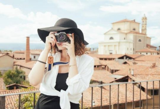 A woman wearing a hat and holding camera