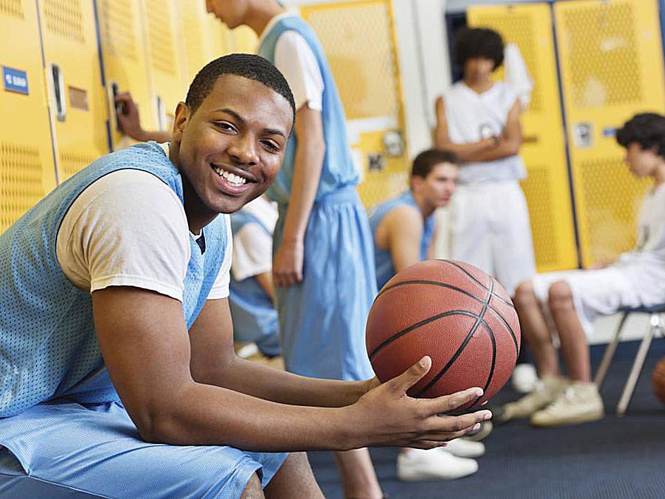 A person sitting on bunch and holding basketball game